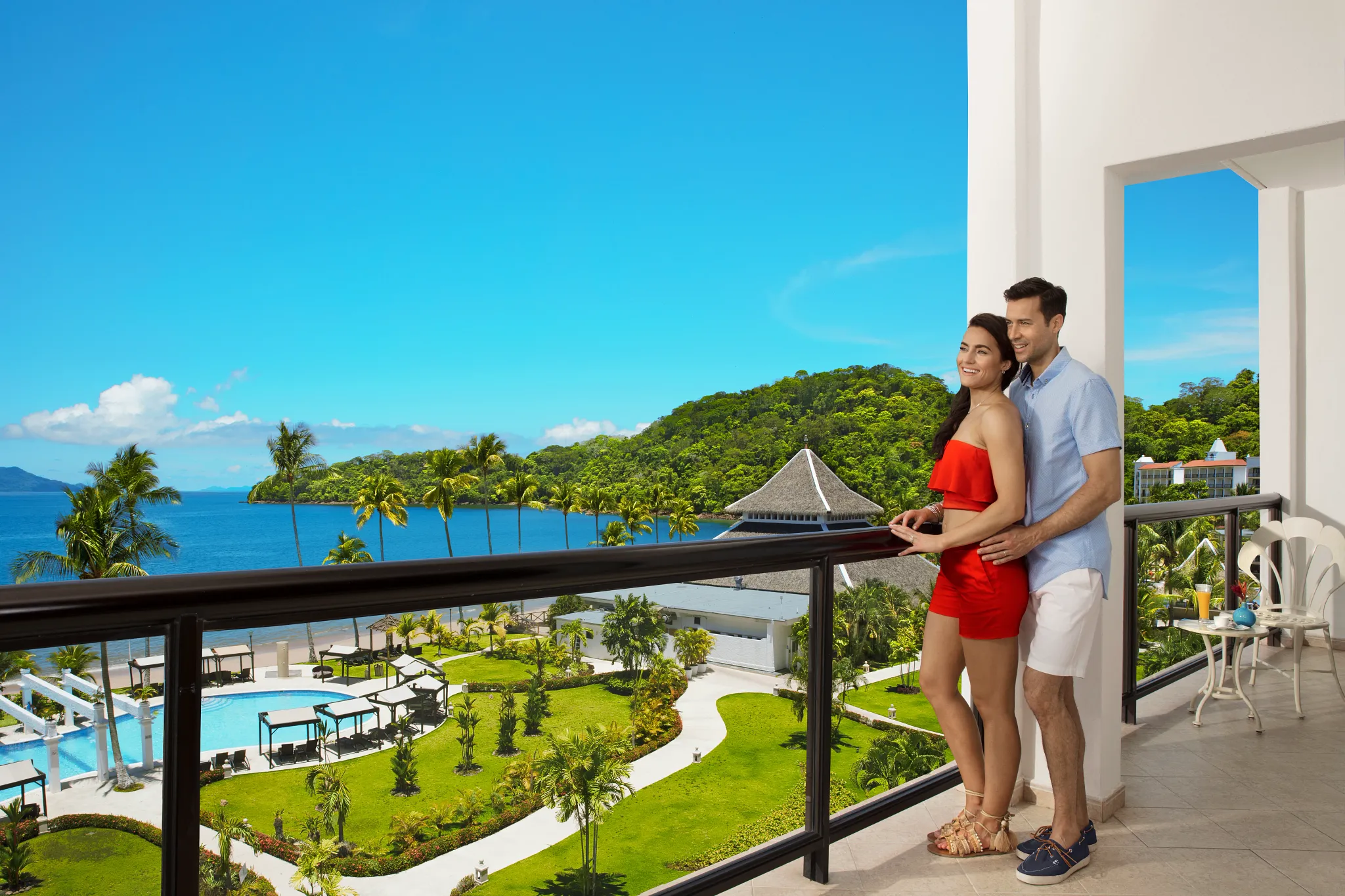 Couple enjoying a romantic balcony view overlooking the ocean and tropical gardens at Dreams Playa Bonita Panama, perfect for couples’ getaways.