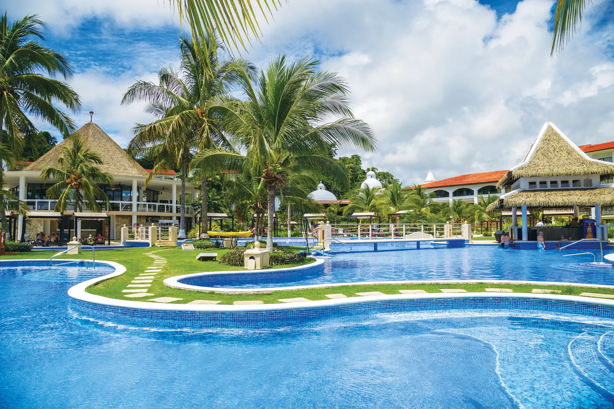 Main resort pool surrounded by palm trees and tropical architecture at Dreams Playa Bonita Panama, offering a relaxing all-inclusive escape.